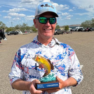 Man holding a fishing champion trophy outdoors.