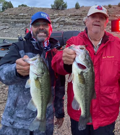 Two men proudly holding large fish they caught.