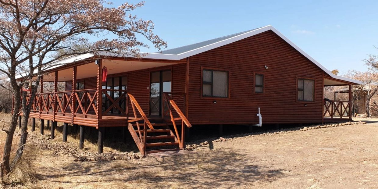 Wooden cabin on stilts in a dry landscape.