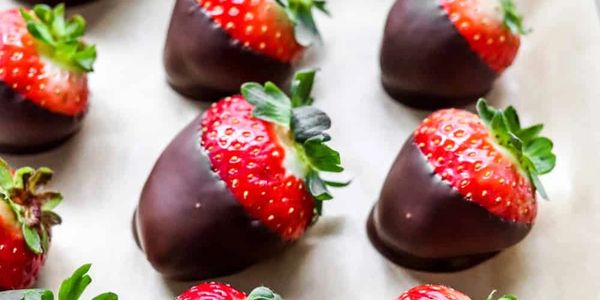 Fresh strawberries dipped in smooth chocolate arranged on a white surface.