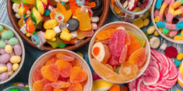 Assorted colorful candies and gummies in bowls.