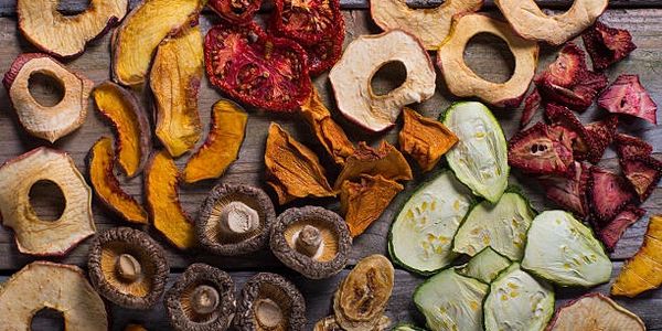 Variety of dried fruits and vegetables arranged on a wooden surface.