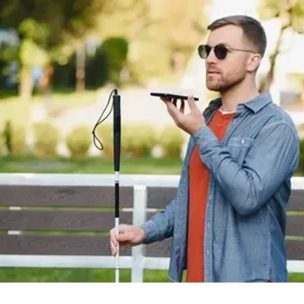 A man holds a long cane in his right hand and holding up a smartphone using it for navigation.