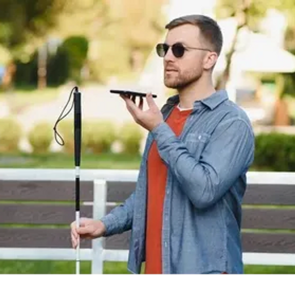 A man holds a long cane in his right hand and holding up a smartphone using it for navigation.