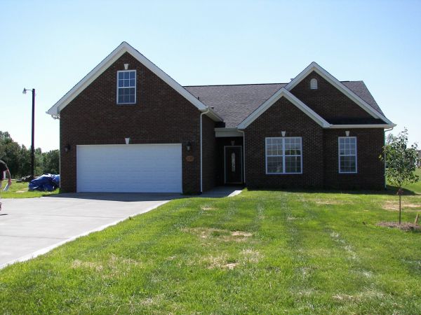A brick house with a large front lawn and a two-car garage.