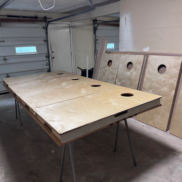 Wooden cornhole boards with holes set up in a garage.