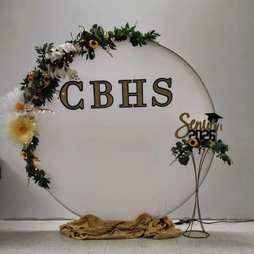 Decorative graduation backdrop with flowers and CBHS letters.