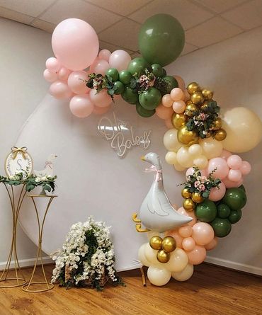Decorative balloon arch with pastel colors and a goose figure for a baby shower.