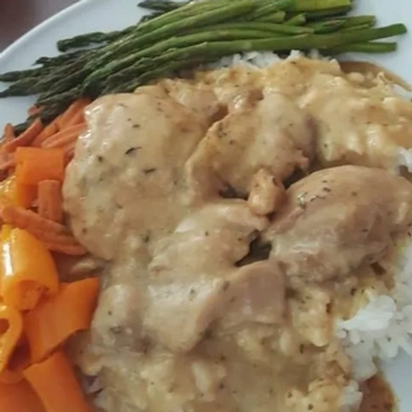 Plate with creamy chicken, white rice, asparagus, carrots, and bell peppers.
