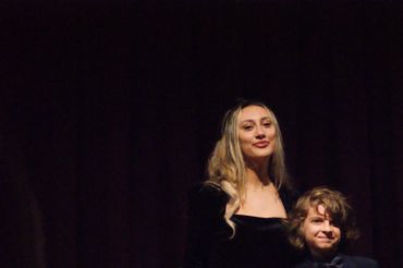 Woman and boy holding diplomas on stage.