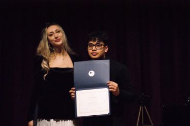 Two people holding a certificate on stage.