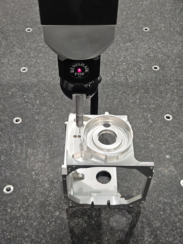 Precision measurement of a metal part using a Renishaw PH9 probe.