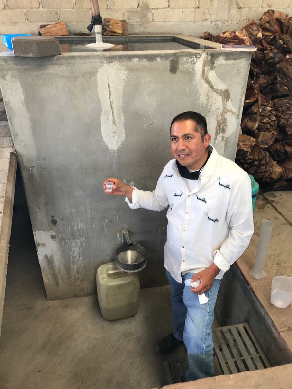 Man holding a small cup near a faucet with water.