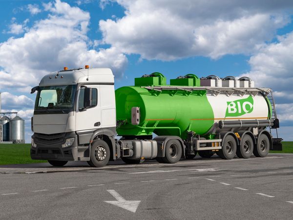 A white truck with a large green tank labeled "BIO" parked on a road