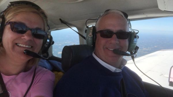Two people wearing headsets inside an airplane cockpit.