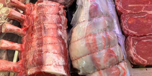 Various cuts of fresh raw meat displayed at a butcher's counter.