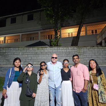 Group of six diverse friends posing together outdoors at night in stylish outfits.