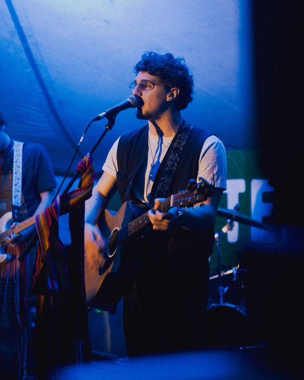 Musician singing and playing guitar on stage.