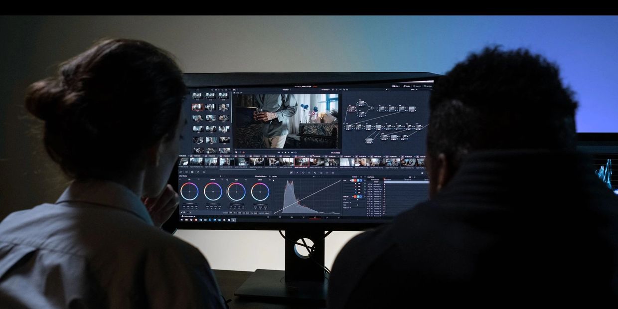 Two people collaborating on video editing and color grading on a computer.