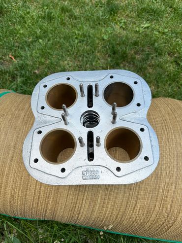 Close-up of a metal engine cylinder head on a cushion outdoors.