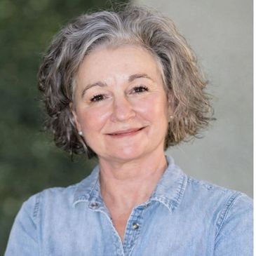 Smiling older woman in a denim shirt.