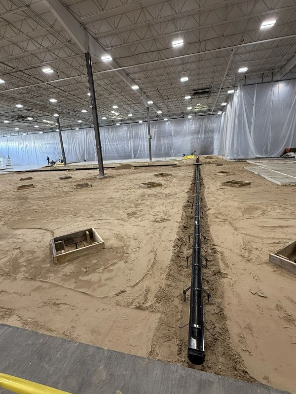 Indoor construction site with sand and steel reinforcements.