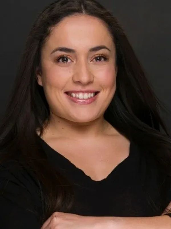 Confident woman with long dark hair smiling warmly, dressed in black.