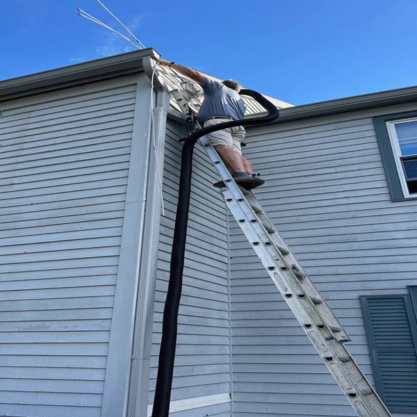 Our professional dryer vent cleaner up on the ladder performing dryer duct cleaning.   