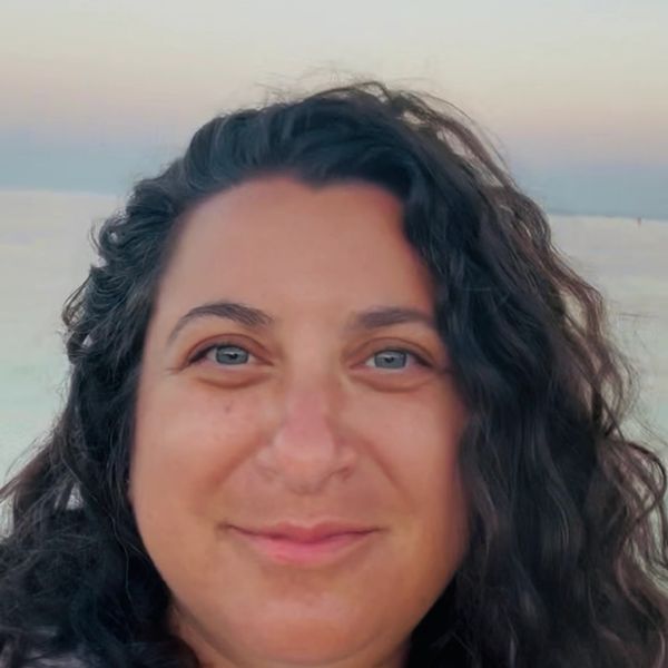 Smiling woman with curly hair at the beach.