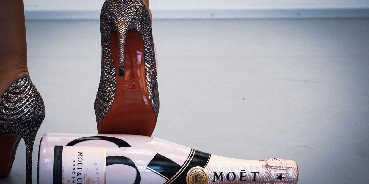 Louboutins stilettos kicking a bottle of Moët & Chandon Champagne across a dance studio floor. 