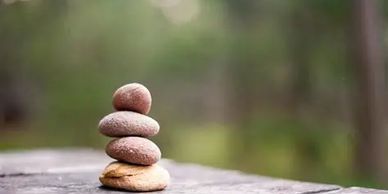 Stack of smooth stones balanced outdoors with blurred green background.