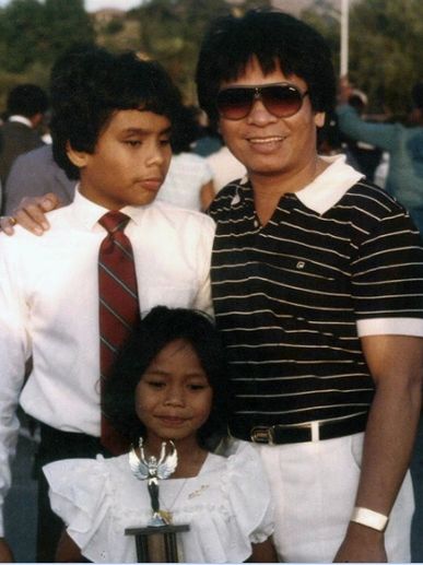 Ollie as a teenger with a white shirt and red tie with his dad and younger sister.