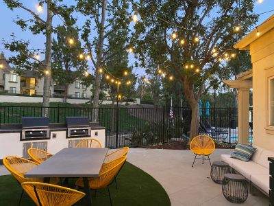 Cozy outdoor dining area with string lights and yellow chairs.