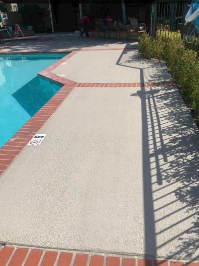 Poolside area with clean deck and metal fence.