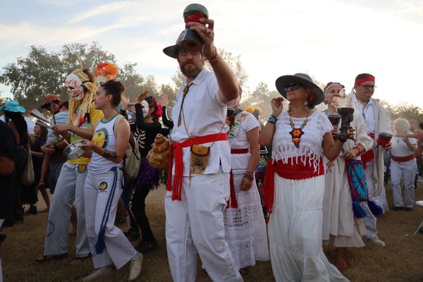 People dressed in traditional attire participating in a cultural ritual outdoors.