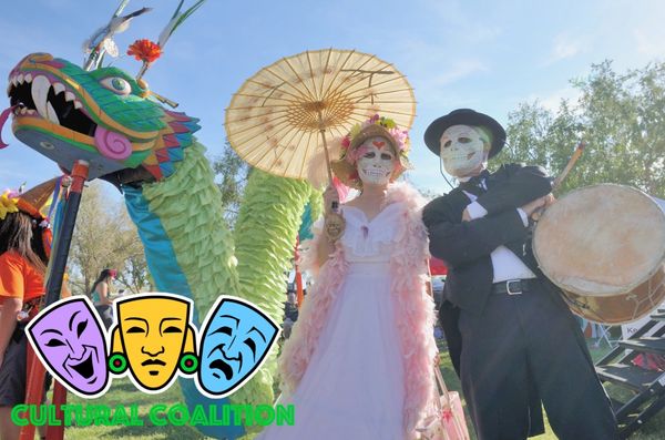 People in Day of the Dead costumes with a colorful dragon figure outdoors.
