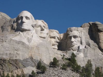 Mount Rushmore with four presidential faces carved in granite under clear blue sky.