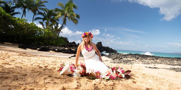 Bride sitting in sand at Makena Cove beach.