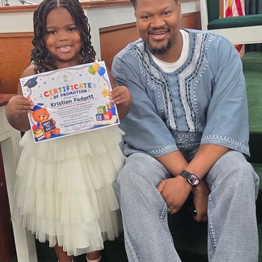Girl holding promotion certificate with man beside her.