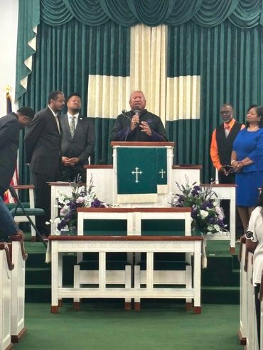 Pastor speaking at church podium with congregation.