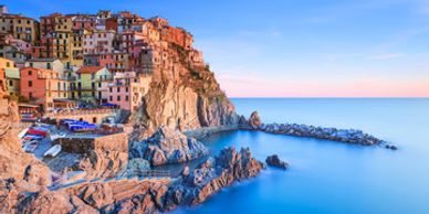 Colorful cliffside village overlooking calm blue sea at sunset.