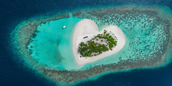 A heart-shaped island surrounded by turquoise waters and coral reefs.
