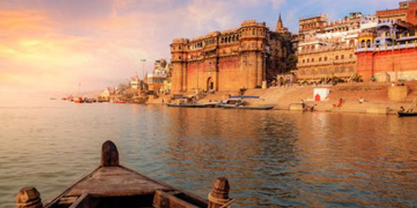 Boat view of historic fort and riverside buildings at sunset.