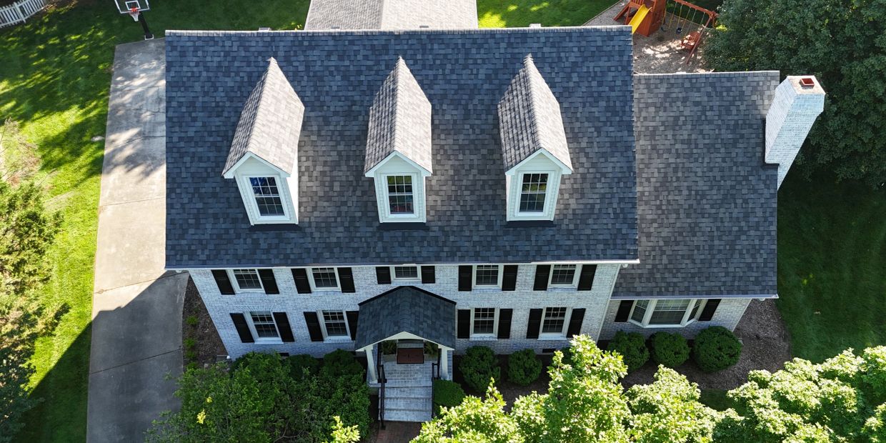 Aerial view of a large house with three dormer windows and a basketball hoop.
