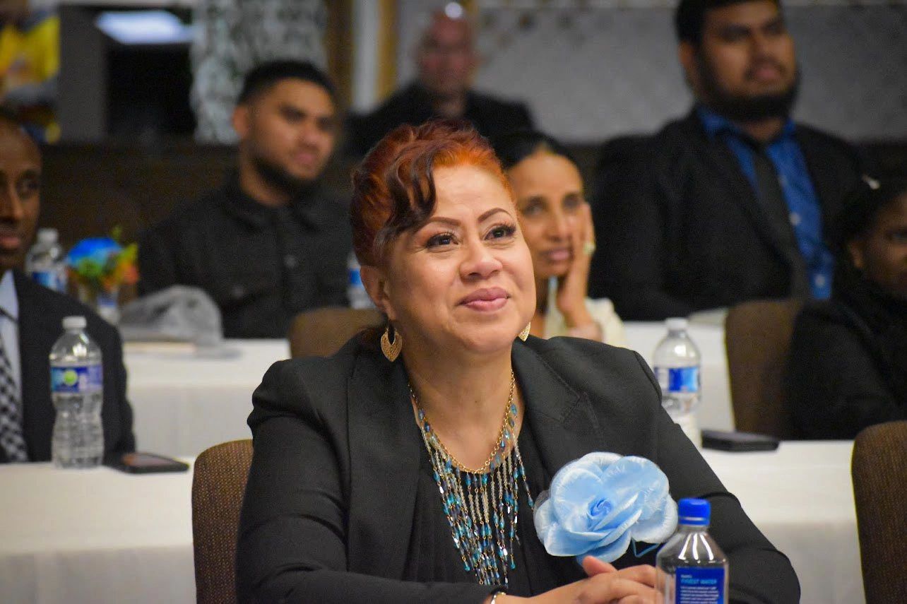 Woman in a black jacket smiling during an event or conference.