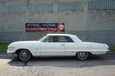 Classic white vintage car parked in front of a wall.