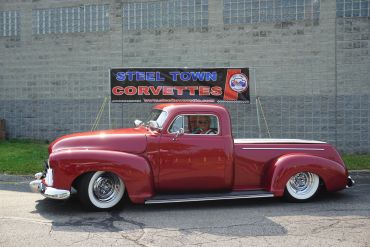 Classic red vintage pickup truck parked outside.