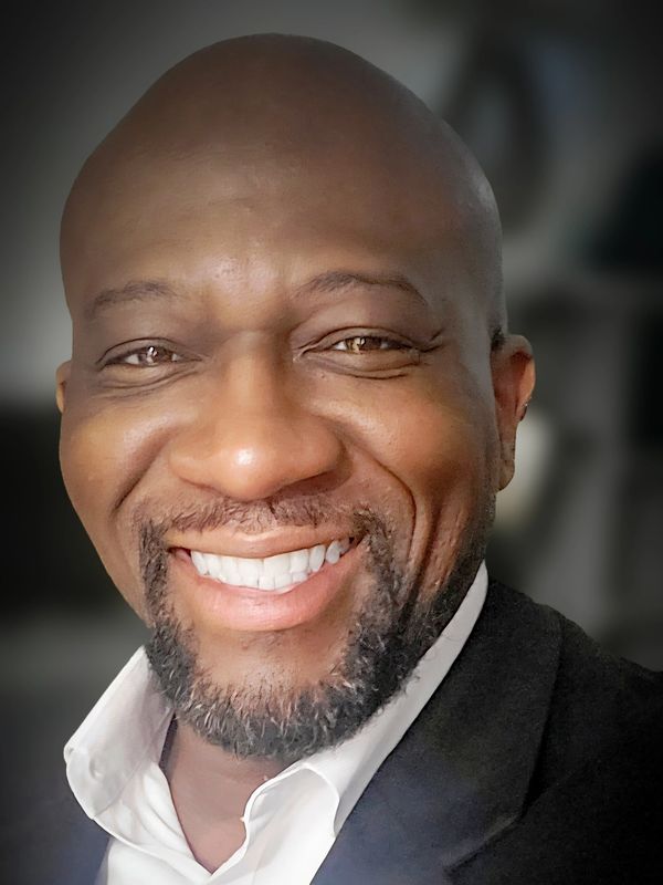 Smiling man in a suit and white shirt, radiating warmth and confidence.