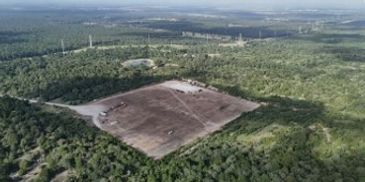 A large cleared land area surrounded by dense forest.