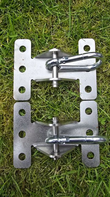 Two metal clamps with pins on grass.